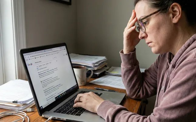 A stressed employee holding her head, surrounded by hands demanding work tasks